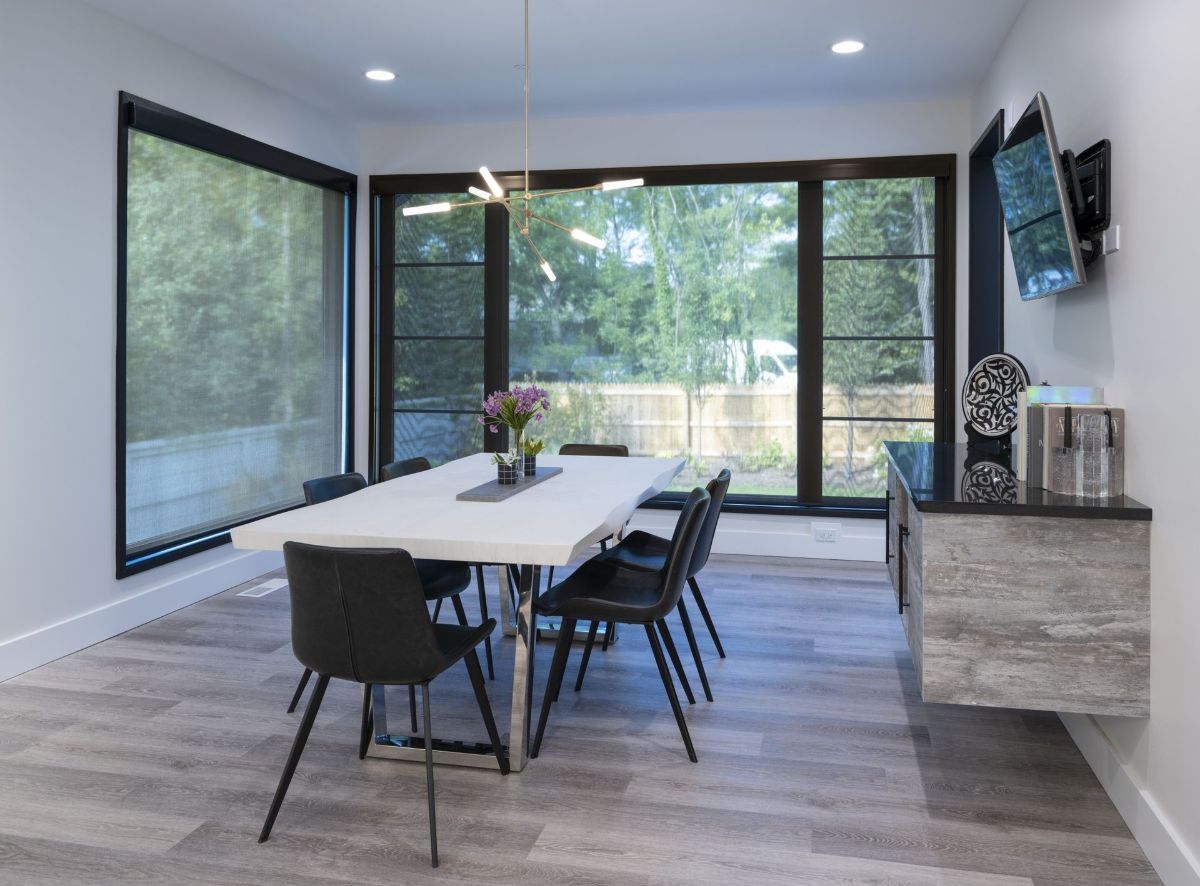 Modern dining room with a table, black chairs, and large windows.