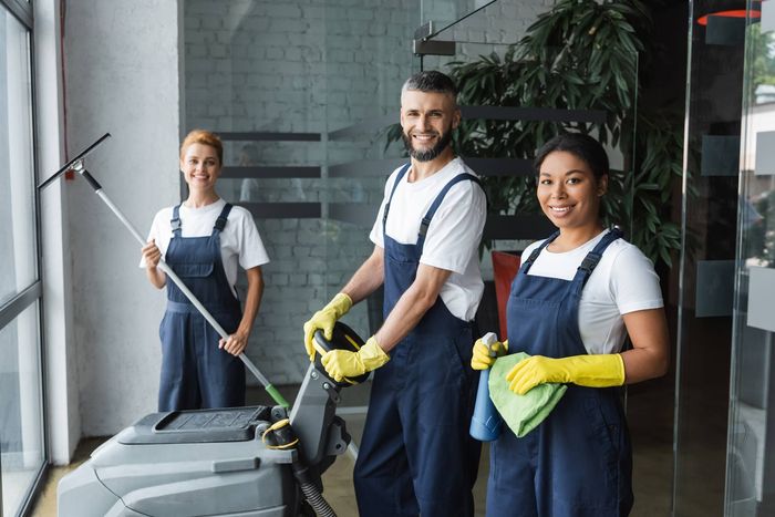 A group of cleaners are standing next to each other in an office