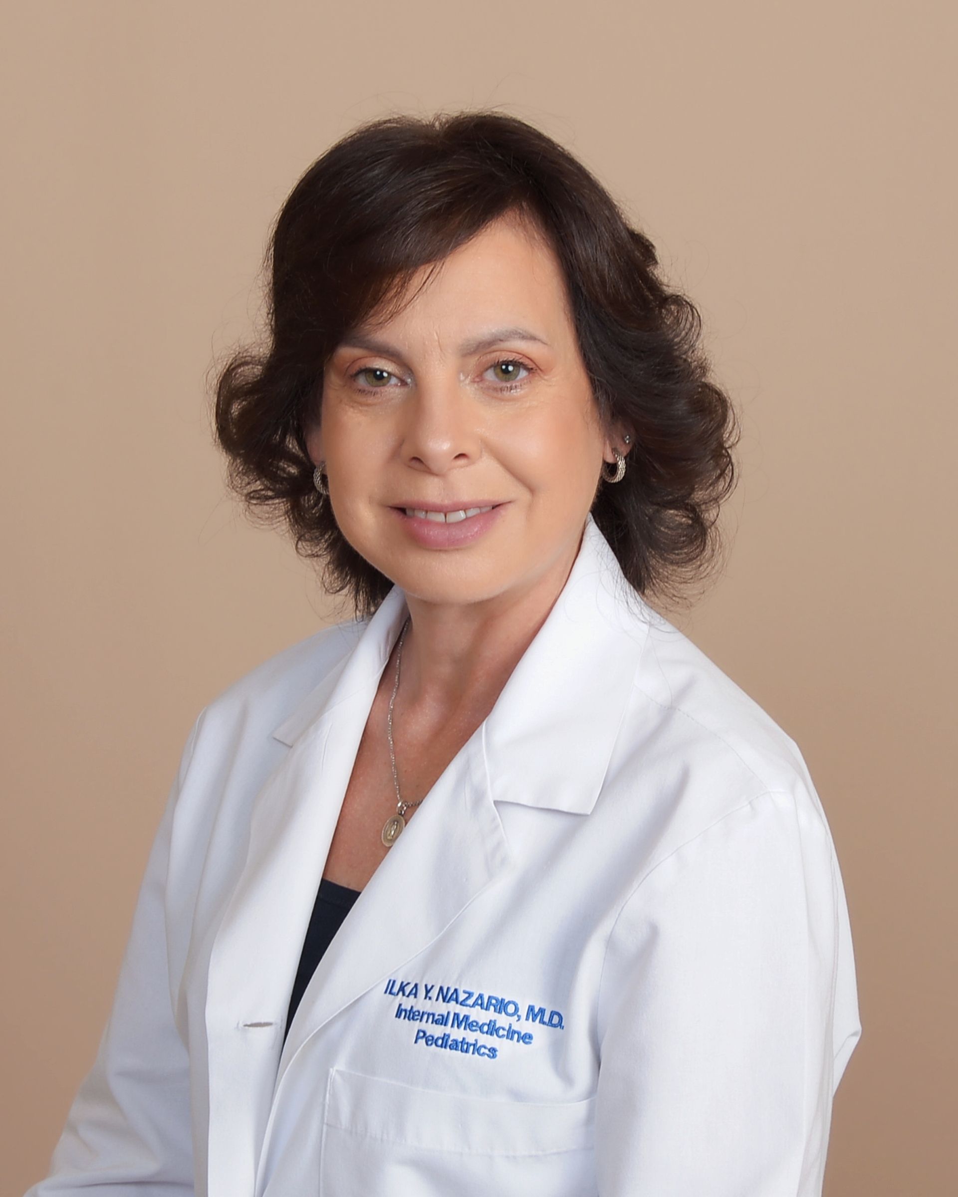 A woman in a white lab coat is smiling for the camera.