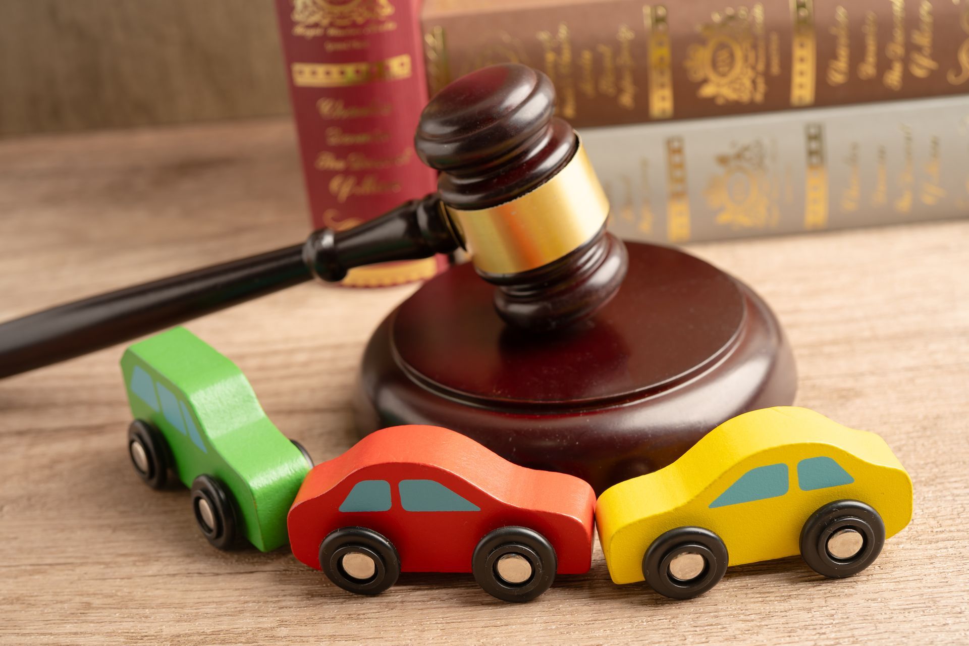 Judge’s gavel behind three toy cars in a rear-end collision, representing a car accident claim