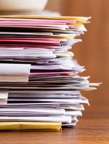 A tall stack of paper files and admissions documents