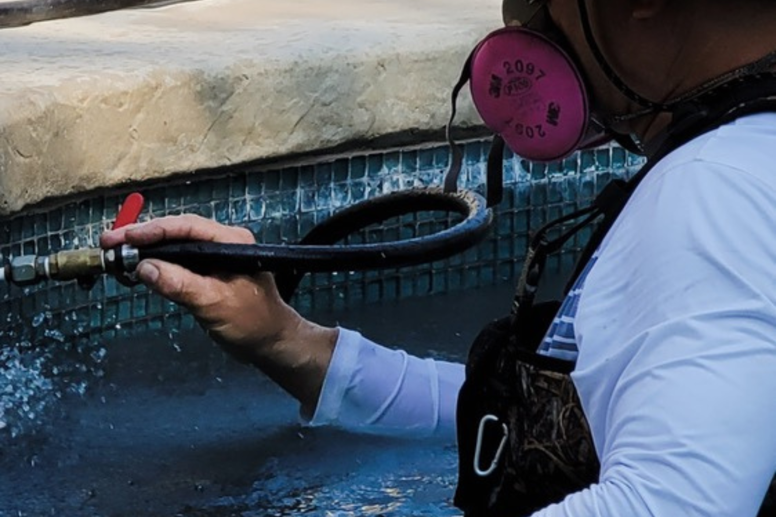 A person wearing headphones is spraying water on a pool