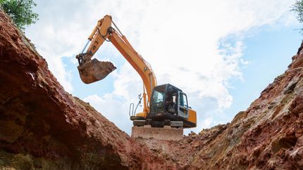 Une grande excavatrice creuse un trou dans le sol.