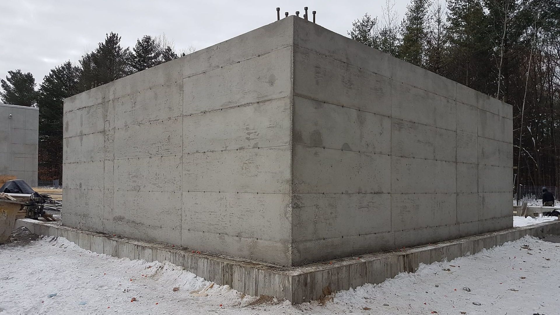 Une grande structure en béton est en cours de construction dans la neige.