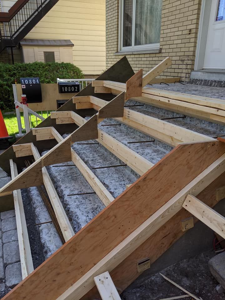 Un escalier en bois est en cours de construction devant un bâtiment en briques