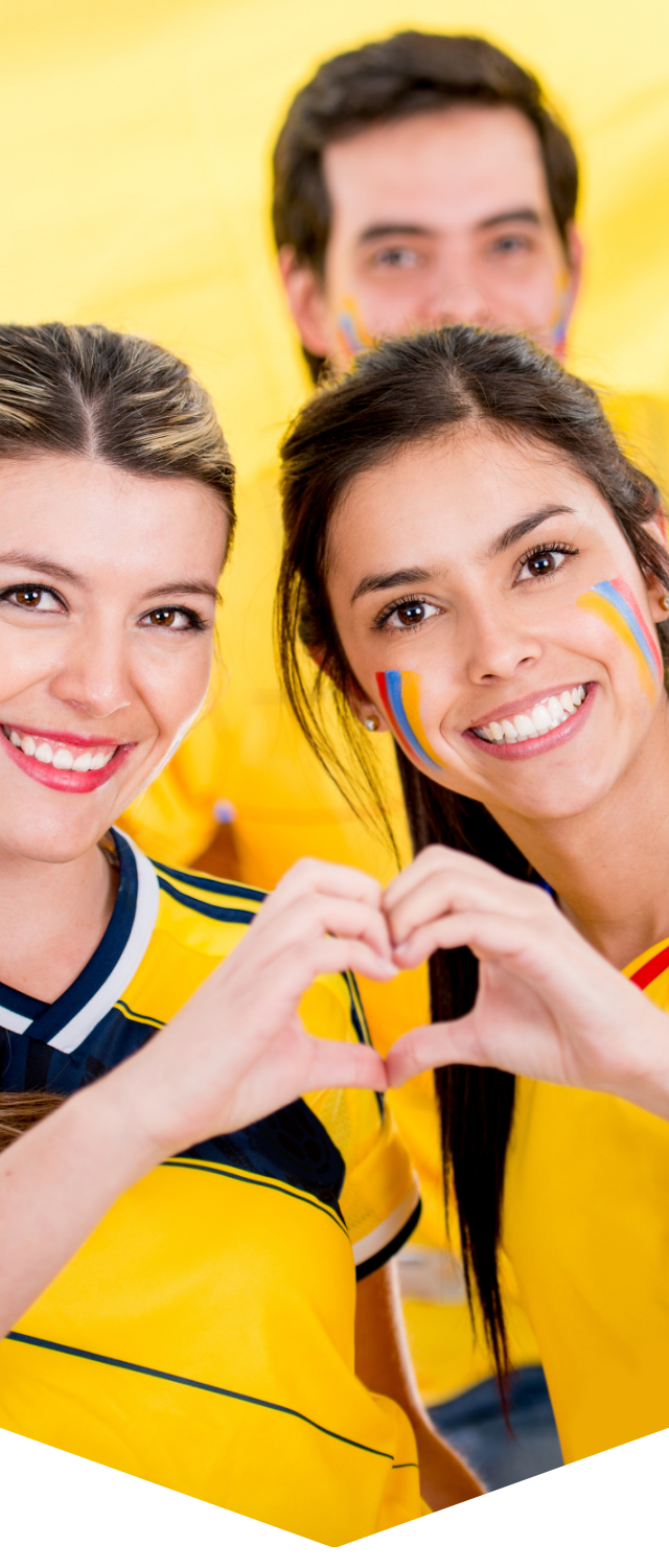 Drie lachende sportfans in gele shirts vormen een hartje met hun handen.