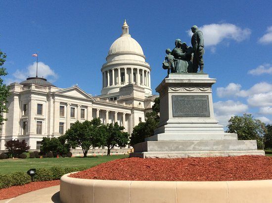 Arkansas State Capitol with statue in foreground, on a sunny day.