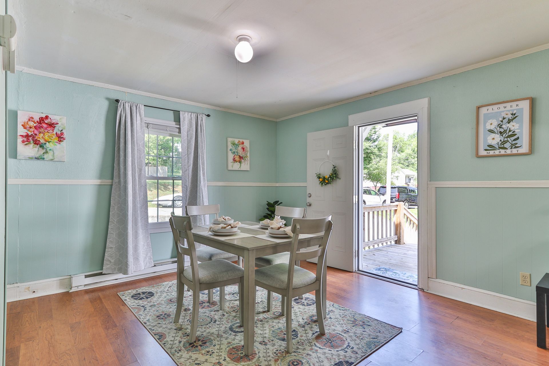 Dining room with mint green walls, wood floor, table and chairs, and open doors to a porch.