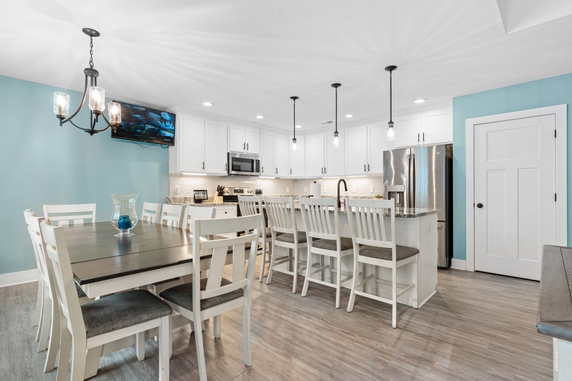 Bright modern kitchen and dining area with white cabinets, blue walls, and stainless steel appliances