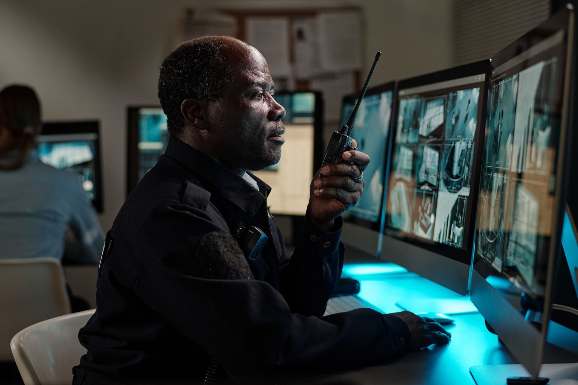 Security analyst reviewing surveillance feeds on multiple monitors in a dimly lit control room