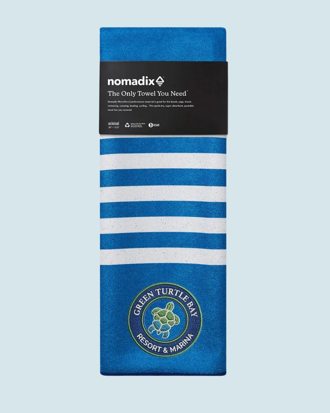 Blue-and-white striped Nomadix towel with black label and circular patch at the bottom.