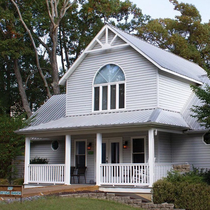 A white house with a gray roof and a porch