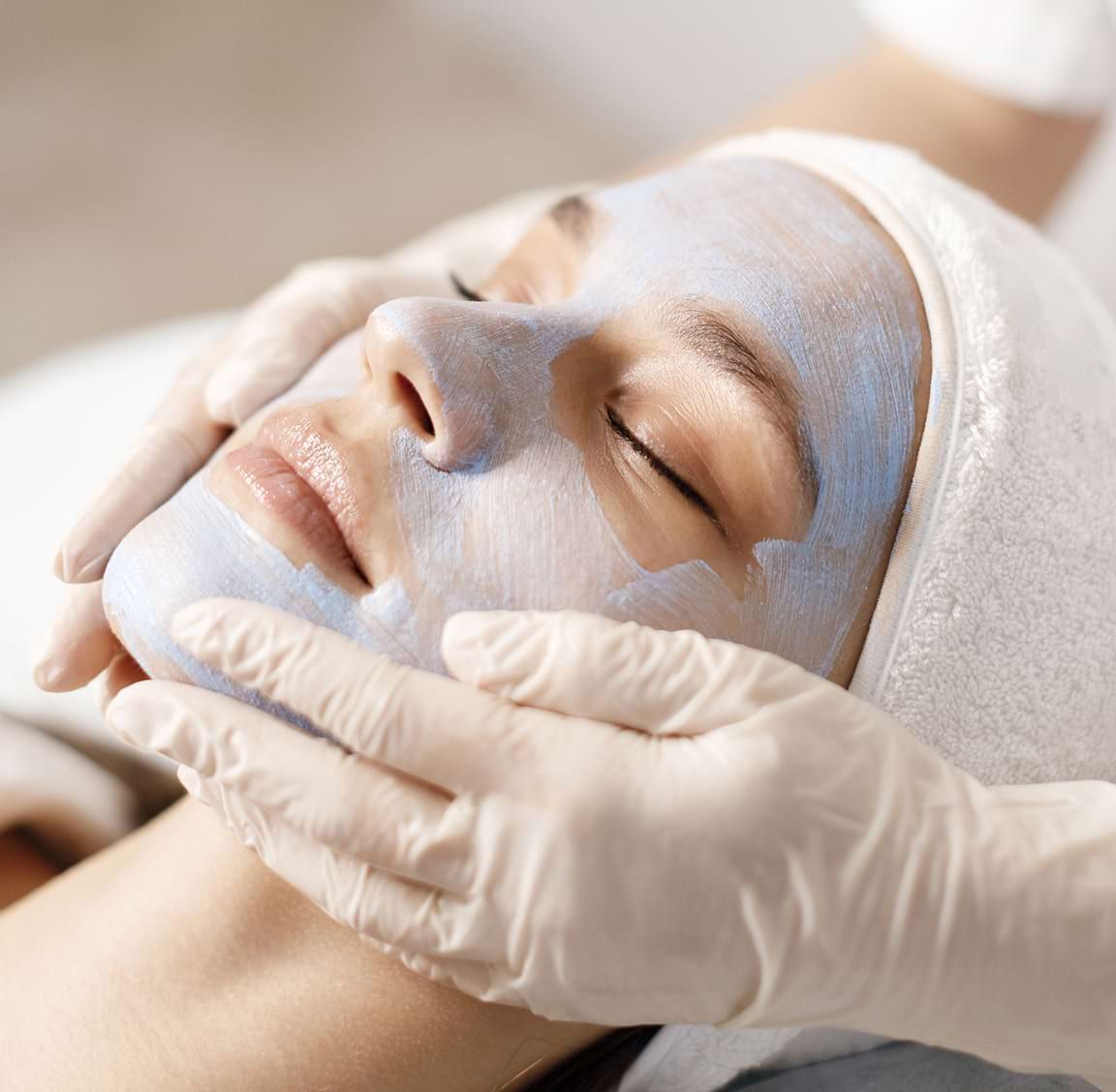 A woman is getting a blue mask on her face