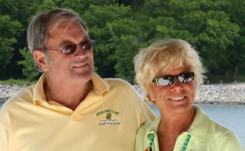 a man and a woman are posing for a picture in front of a body of water .