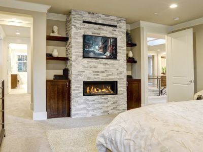 A bedroom with a fireplace and a flat screen tv.
