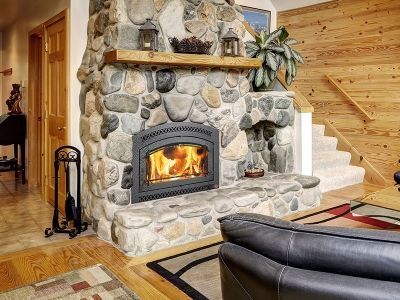 A living room with a stone fireplace and stairs.