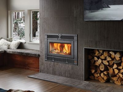A living room with a fireplace and a pile of wood.