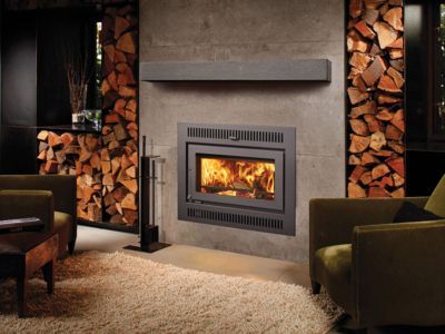 A living room with a fireplace and a pile of wood on the wall.