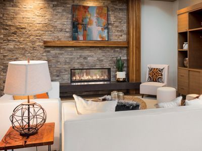 A living room with a fireplace , couch , chairs and a lamp.