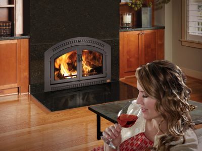 A woman is drinking wine in front of a fireplace.