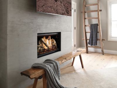 A living room with a fireplace and a bench with a blanket on it.