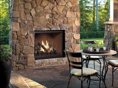 A stone fireplace with a table and chairs in front of it