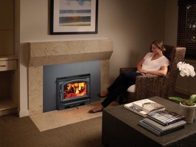 A woman is sitting in a chair in front of a fireplace.