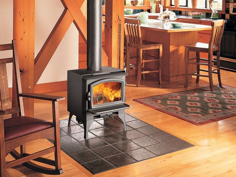 A wood stove is sitting in a living room next to a rocking chair.