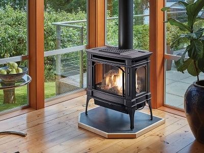 A wood stove is sitting in a living room next to a window.