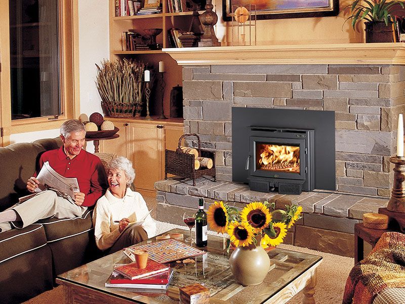 A man and woman are sitting on a couch in front of a fireplace.