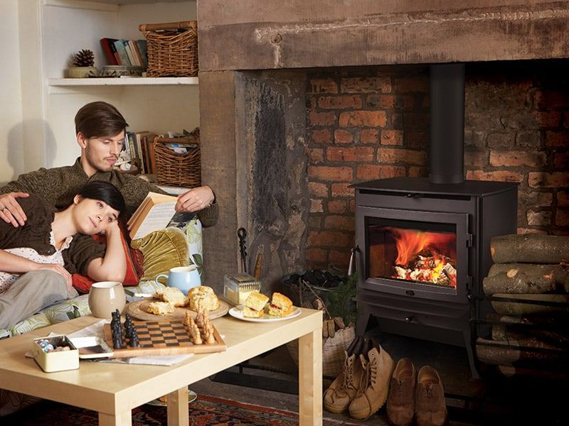 A man and a woman are sitting in front of a fireplace.