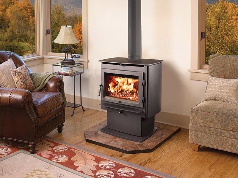 A wood stove is sitting in a living room next to a leather chair.