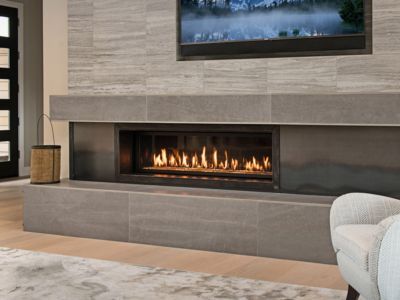 A living room with a fireplace and a television on the wall.