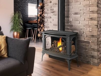 A gas fireplace is sitting in a living room next to a brick wall.