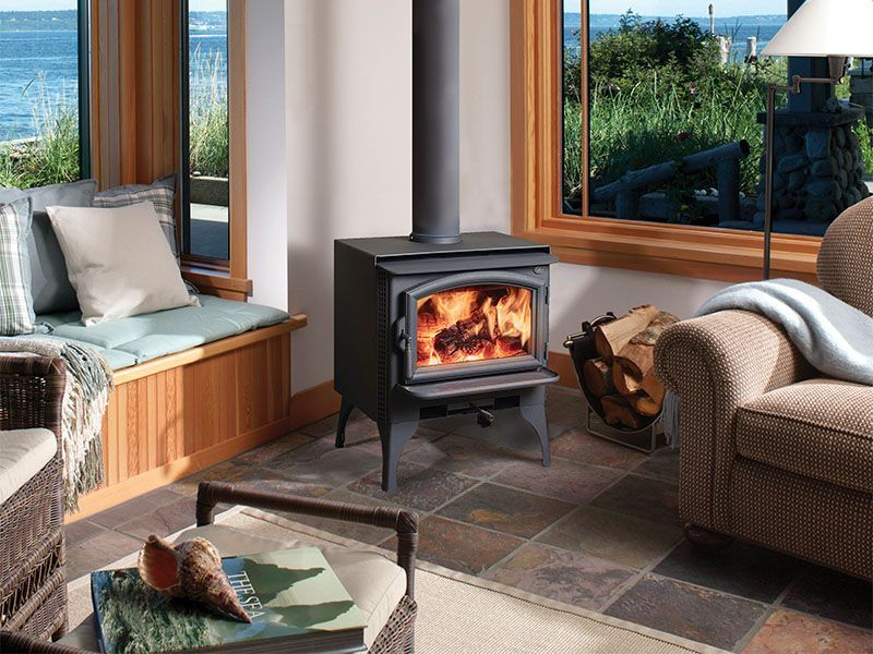 A living room with a wood stove and a view of the ocean