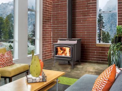 A living room with a wood stove and a brick wall.