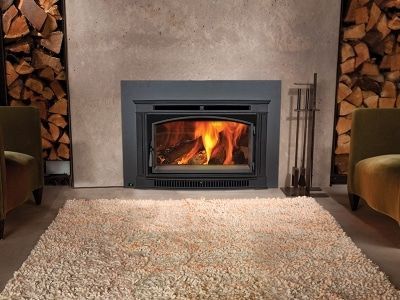 A living room with a fireplace and a pile of logs behind it