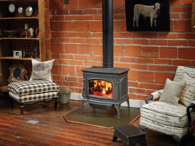 A wood stove is sitting in a living room next to a brick wall.