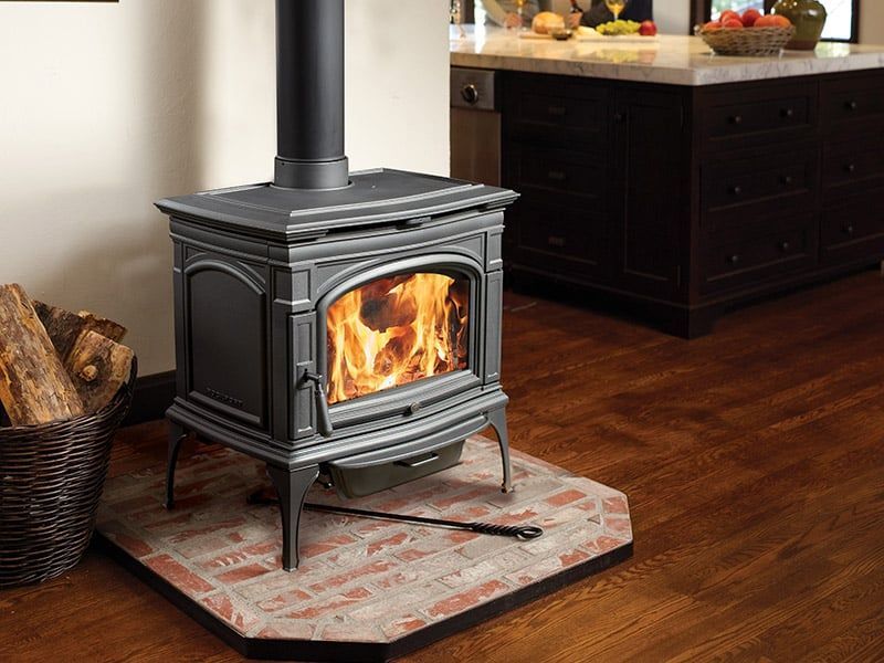 A wood stove is sitting on a brick floor in a kitchen.