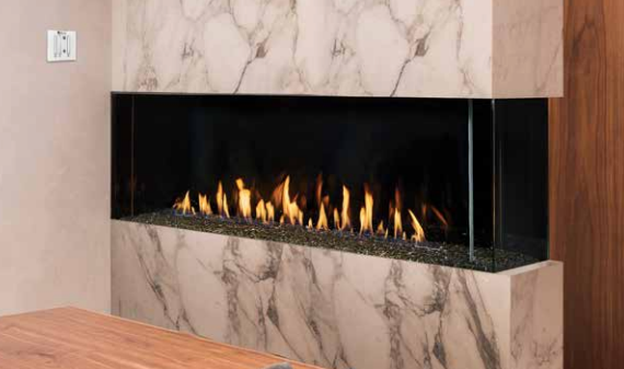 A fireplace with a marble wall and a wooden table in a living room.
