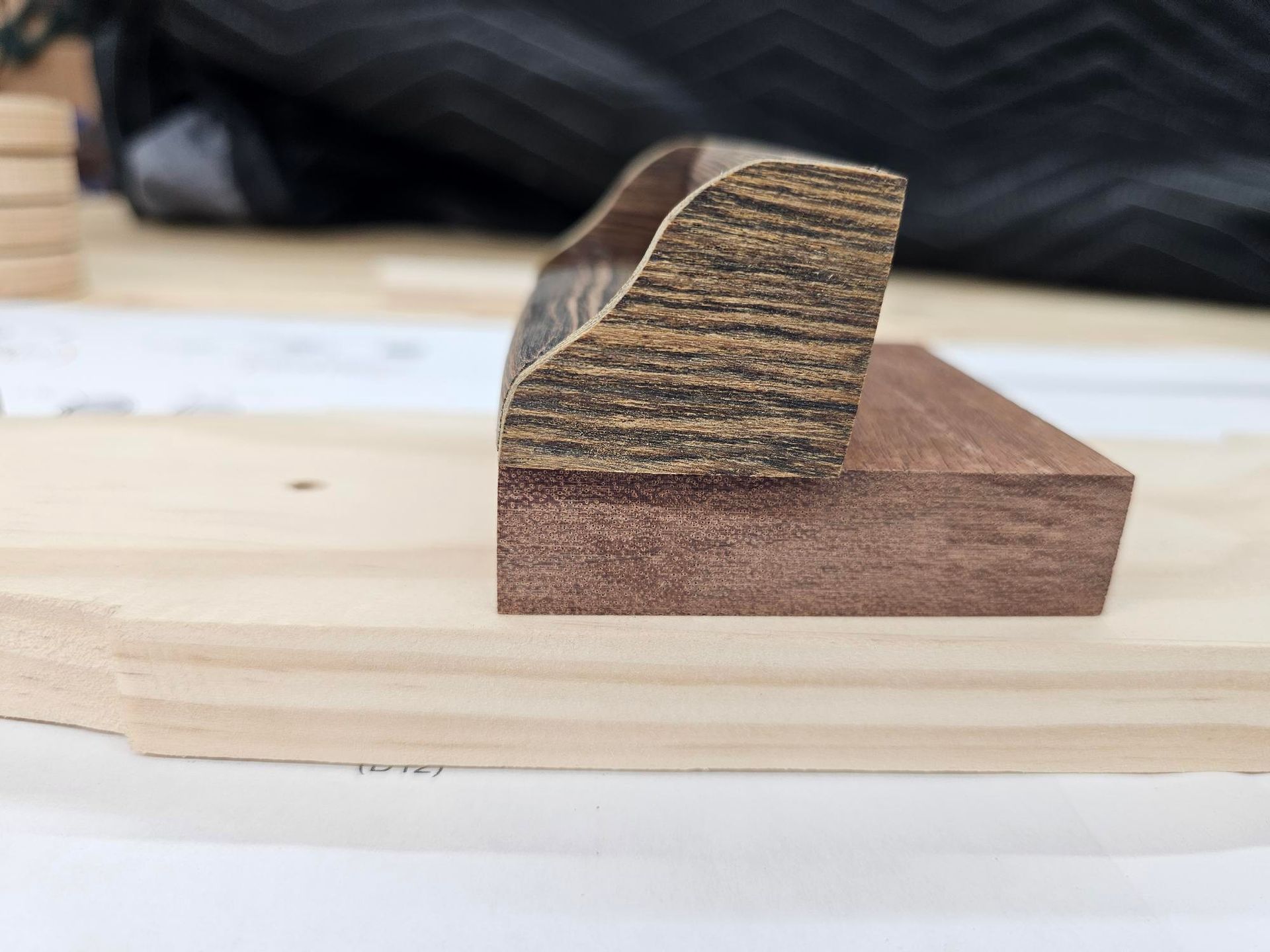 Wooden piece with dark, textured top and red-brown base, resting on light wood surface.