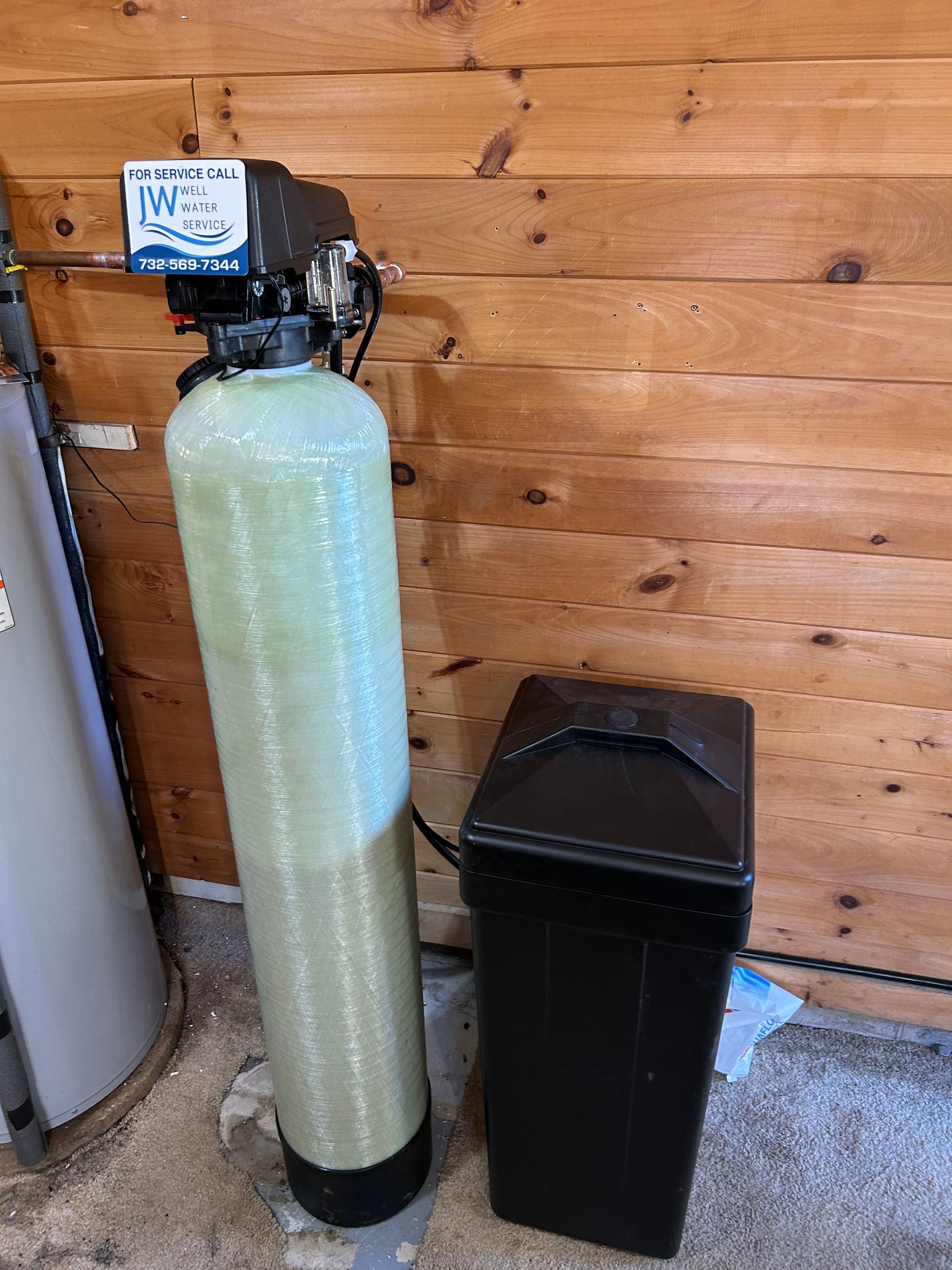Water softener system in a wooden-walled utility room.