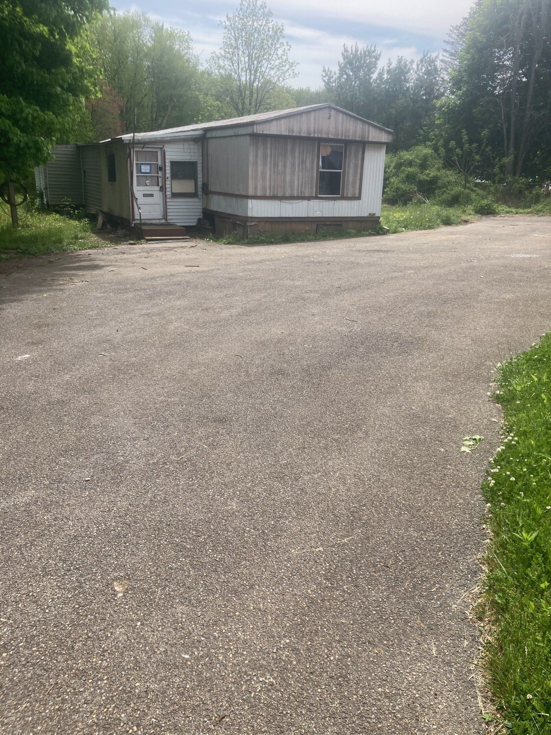 A mobile home is parked in the middle of a gravel driveway.