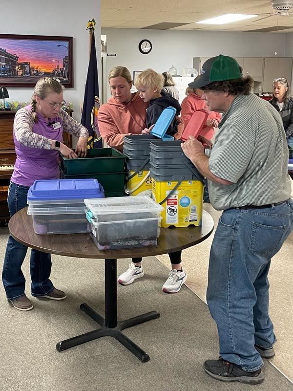 group watching a woman working with dirt/soil in a classroom setting