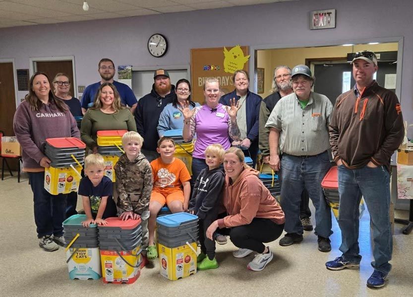 group of men, women, and children posing for a group photo in a classroom setting