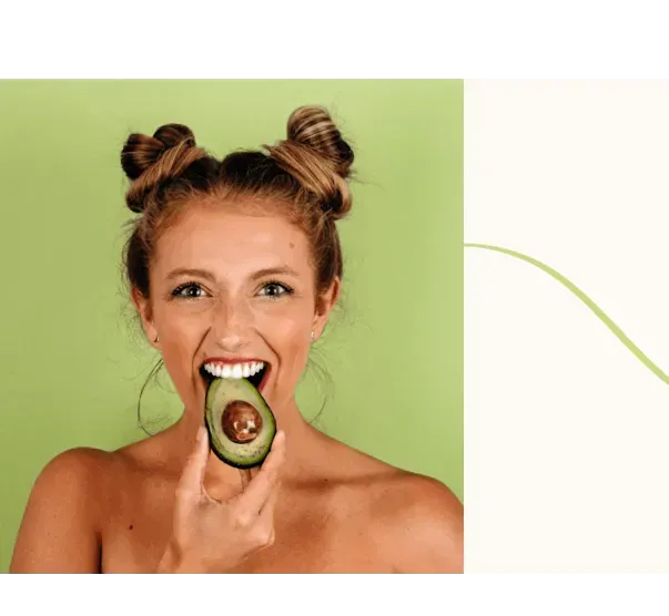 A woman is holding a slice of avocado in her mouth.