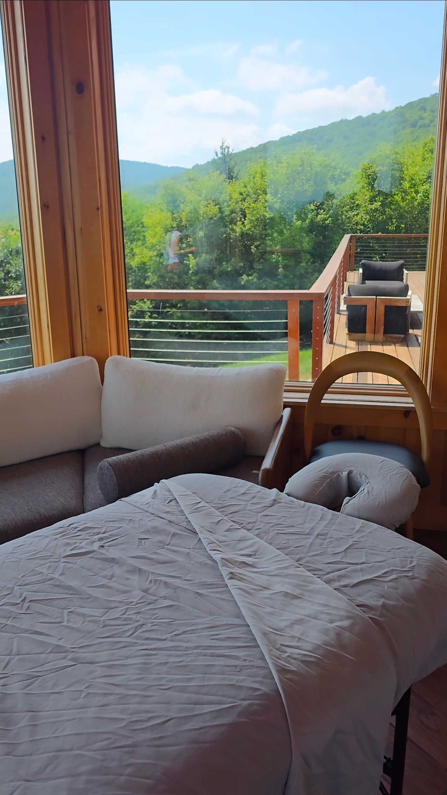 Cozy bed on a balcony with mountain and forest views beyond wooden railings Cozy bed on a balcony with mountain and forest views beyond wooden railings