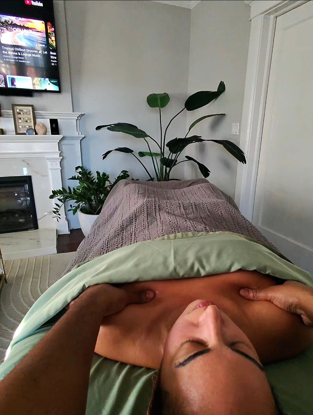 Person receiving a facial massage with eyes closed on a spa bed