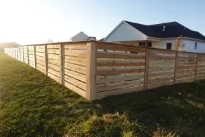 Wooden fenced yard beside a house on a grassy lot at sunset