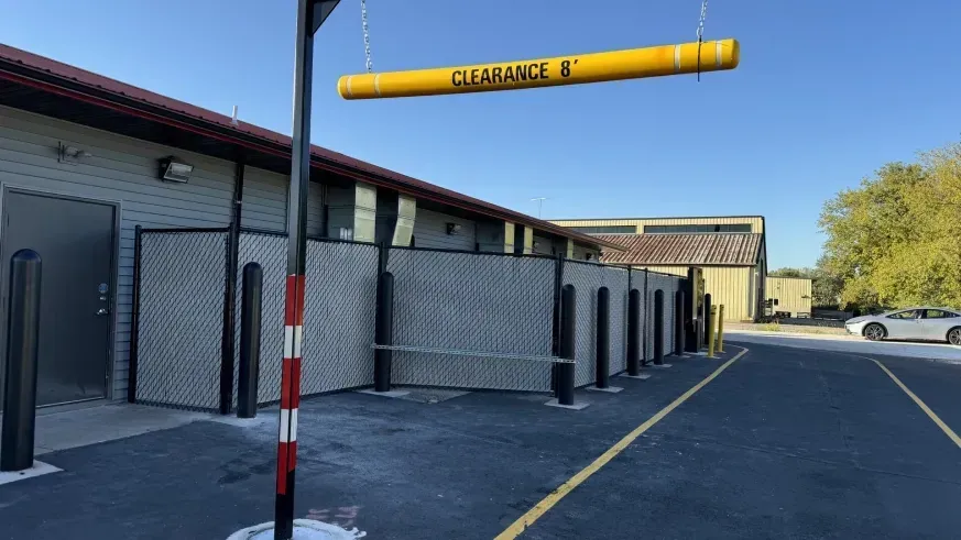 Drive-thru lane beside a brick building with yellow clearance bar and parking lot.